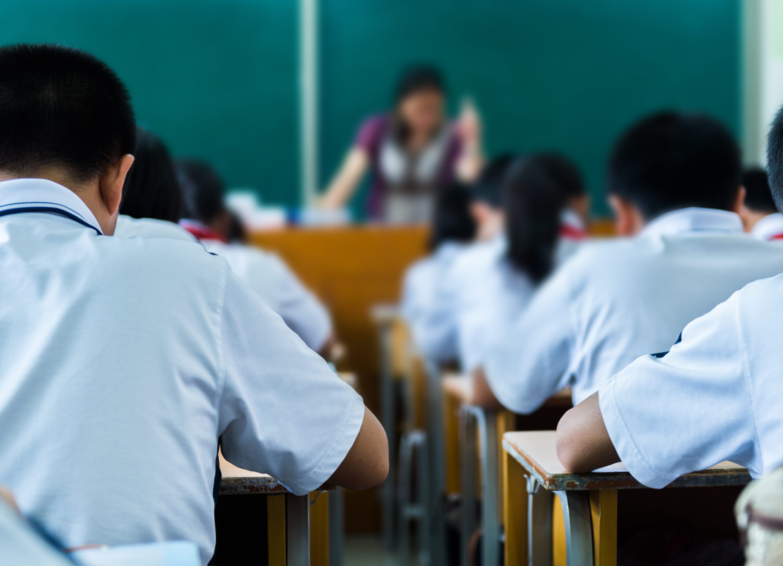 Rear view of middle school students studying in classroom.